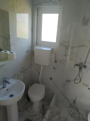 a bathroom with a toilet and a sink and a window at Hostel Vera - Airport Podgorica in Podgorica