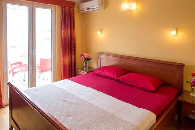 a bedroom with a large bed with red pillows on it at Apartmani Becici in Becici