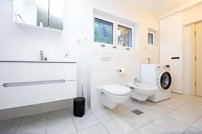 a white bathroom with a toilet and a washing machine at Villa M&M in Budva