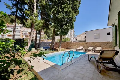 a swimming pool with a chair next to a house at Mediterranean vacation home with pool Petrovac in Budva