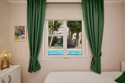 a bedroom with a window with green curtains at Mediterranean vacation home with pool Petrovac in Budva
