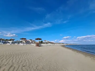 a beach with umbrellas and chairs and the ocean at Down Town Studio in Ulcinj