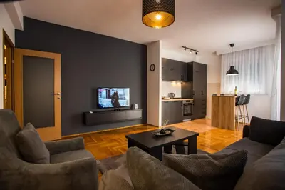 a living room with a couch and a tv on a wall at Apartment Podgorica in Podgorica