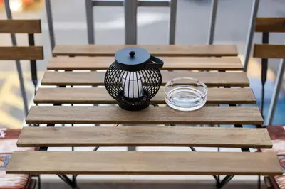 a group of wooden benches with a lantern and a glass at Apartment Podgorica in Podgorica