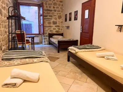 a room with two beds and a table and a chair at Old Town Homestel in Kotor