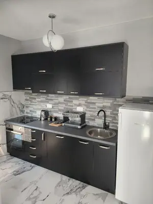 a kitchen with black cabinets and a sink and a refrigerator at Adriatic Oasis in Bar