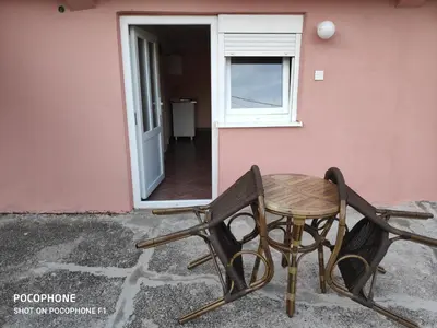 a table and chair sitting next to a pink wall at Apartman Pavle 2 in Virpazar