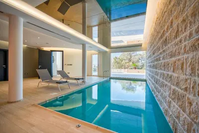 a swimming pool in a house with two chairs at Villa Solaria in Sveti Stefan