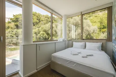 a bedroom with a bed and large windows at Villa Solaria in Sveti Stefan