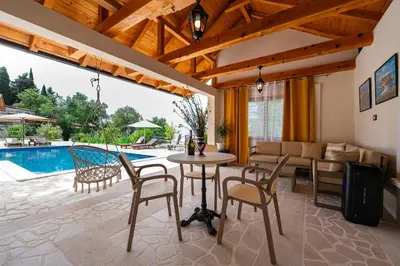 a living room with a table and chairs and a pool at Sunset & Sunrise Villas in Stanisici-Two Villas With Common Pool in Budva