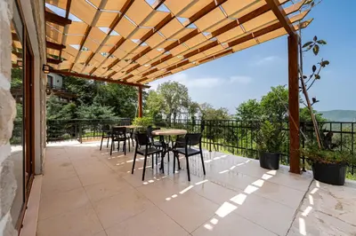 a patio with a table and chairs under a wooden pergola at Sunset & Sunrise Villas in Stanisici-Two Villas With Common Pool in Budva