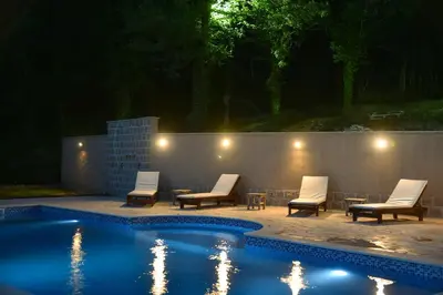 a patio with chairs and a pool at night at Sunset & Sunrise Villas in Stanisici-Two Villas With Common Pool in Budva