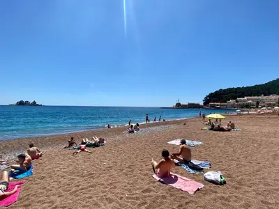 a group of people sitting on a beach at Family Beachfront Apartment in Petrovac na Moru