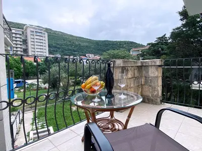 a glass table with a bowl of fruit on a balcony at Family Beachfront Apartment in Petrovac na Moru