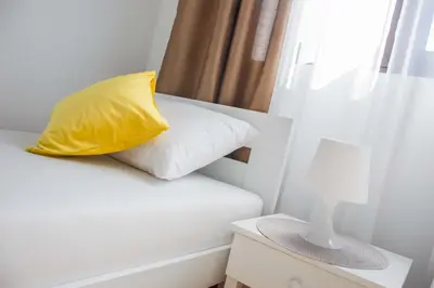 a yellow pillow sitting on a bed next to a window at Ana's Place in Kotor