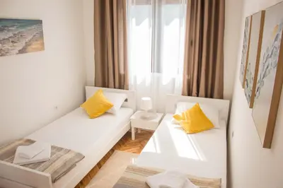 a room with two white benches with yellow pillows at Ana's Place in Kotor