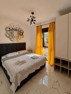 a bedroom with a bed and yellow curtains at Apartment Tulip of Becici in Budva