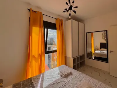 a bedroom with orange curtains and a bed and a window at Apartment Tulip of Becici in Budva