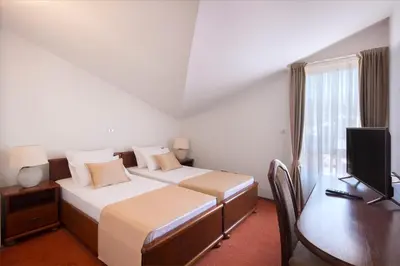 a bedroom with two beds and a desk and a television at Villa Ljubanovic in Budva