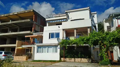 a white building with a tree in front of it at Apartments Abramovic 2 in Sutomore