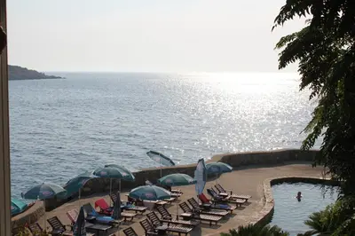 a group of chairs and umbrellas next to the water at Anna Apartment in Utjeha
