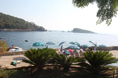 a beach with umbrellas and people sitting on the beach at Anna Apartment in Utjeha