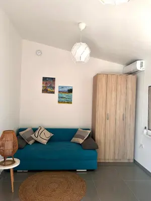 a living room with a blue couch and a wooden cabinet at Anna Apartment in Utjeha