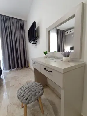 a bathroom with a vanity with a mirror and a stool at MD APARTMENTS in Ulcinj