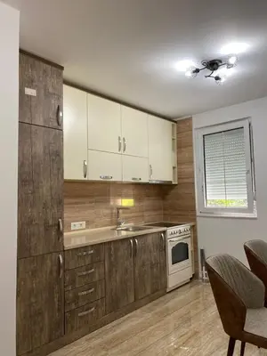 a kitchen with wooden cabinets and a sink and a stove at Apartman 02 in Bar
