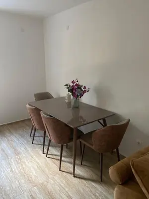 a dining room table with chairs and a vase of flowers at Apartman 02 in Bar