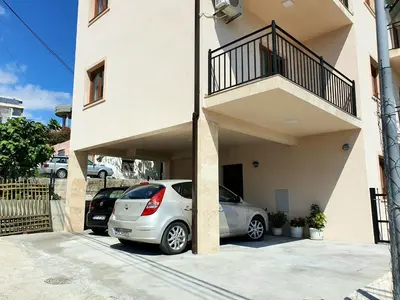 a white car parked in a parking lot next to a building at Family Apartments in Bar