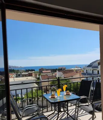 a table on a balcony with a view of the ocean at Family Apartments in Bar