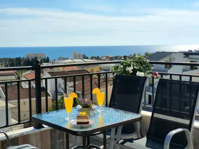 a table on a balcony with a view of the ocean at Family Apartments in Bar