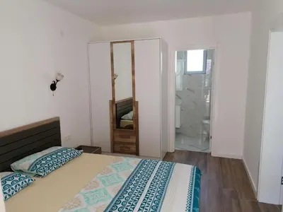 a white bedroom with a bed and a mirror at Riki Dream in Dobra Voda
