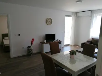 a living room with a table and a television at Riki Dream in Dobra Voda