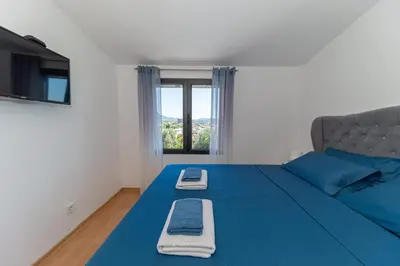 a bedroom with a blue bed and a window at Guest House Luksic in Bar