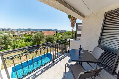 a balcony with a table and chairs and a swimming pool at Guest House Luksic in Bar