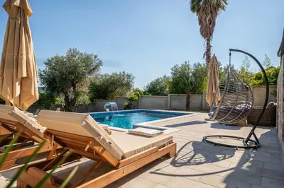 a swimming pool with two chairs and an umbrella at Guest House Luksic in Bar