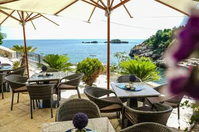 a restaurant with tables and chairs and a view of the ocean at BUZUKU Apartments Liman (Mediterraneo) in Ulcinj