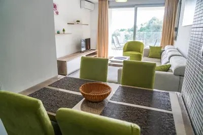 a living room with a table and green chairs at BUZUKU Apartments Liman (Mediterraneo) in Ulcinj
