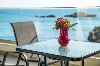 a red vase with flowers sitting on a table at BUZUKU Apartments Liman (Mediterraneo) in Ulcinj