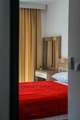 a bedroom with a red bed and a mirror at BUZUKU Apartments Liman (Mediterraneo) in Ulcinj