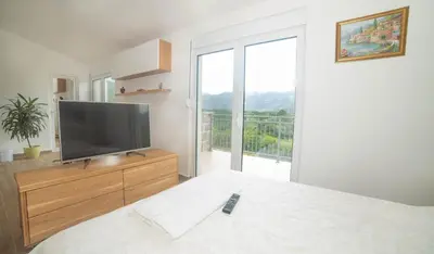 a bedroom with a flat screen tv on a dresser at Plamenatz studio apartments in Virpazar