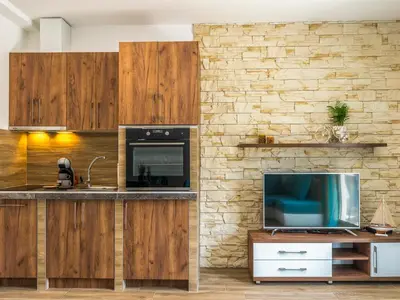 a kitchen with a tv and a stone wall at Square Point Apartments in Kotor