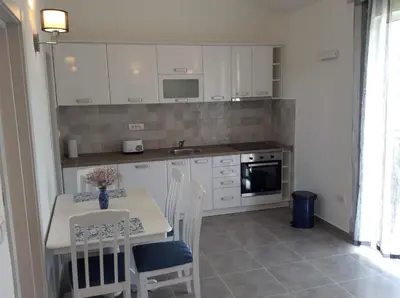 a kitchen with white cabinets and a table and chairs at Apartments Raskovic I in Radanovići
