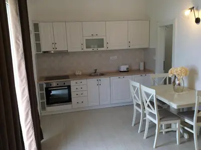 a kitchen with white cabinets and a table with chairs at Apartments Raskovic I in Radanovići