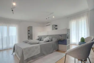 a bedroom with a bed and some chairs and windows at Fontana Seafront Residences in Budva