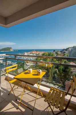 a yellow table and chairs on a balcony with a view of the ocean at Fontana Seafront Residences in Budva