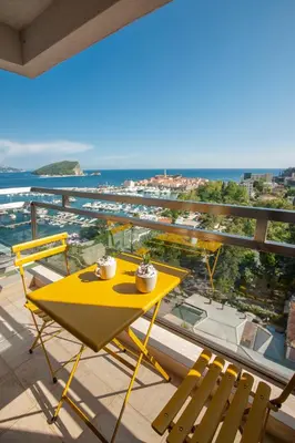 a yellow table and chairs on a balcony with the ocean at Fontana Seafront Residences in Budva