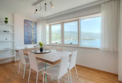 a dining room with a table and chairs and a large window at Fontana Seafront Residences in Budva